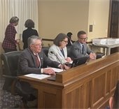 Ken Sorensen, Patty Acomb and Jeff Dahl sitting at desk talking into microphones at the State Capital