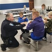 pd chief marc schultz kneeling down talking to kids eating lunch at school