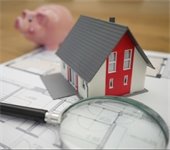 house model next to piggy bank and magnifying glass