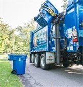 blue garbage truck picking up garbage