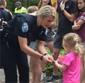 wayzata woman police officer handing a little girl a sticker
