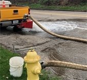 hose hooked up to hydrant with water in the street