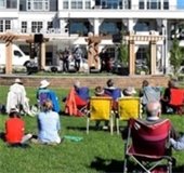 people sitting in chairs on the grass listening to music